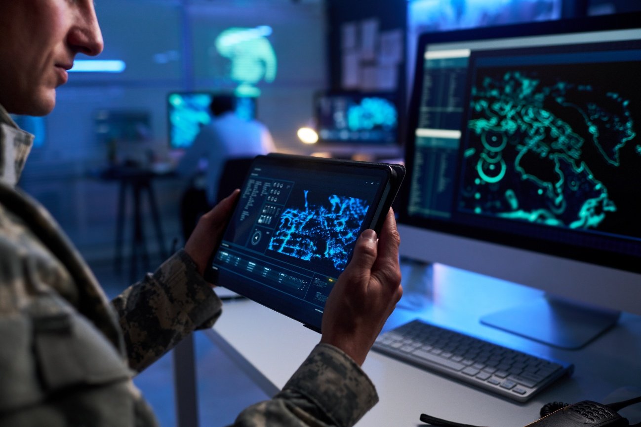 Profesional consultando un panel de datos e inteligencia geoespacial en una tableta, en un entorno de seguridad y defensa